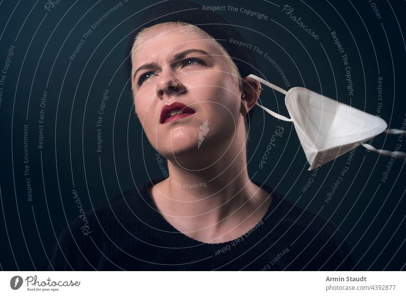 Studio portrait of a young woman who frees herself from the corona protective mask studio serious confident looking irritated refuse strong powerful piercing