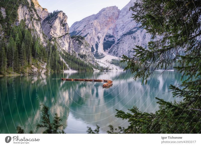 Wooden rowing boats at calm lake Braies or Pragser Wildsee during sunset pink light. Dolomites, Italy braies pragser wildsee wooden travel nature tourism italy