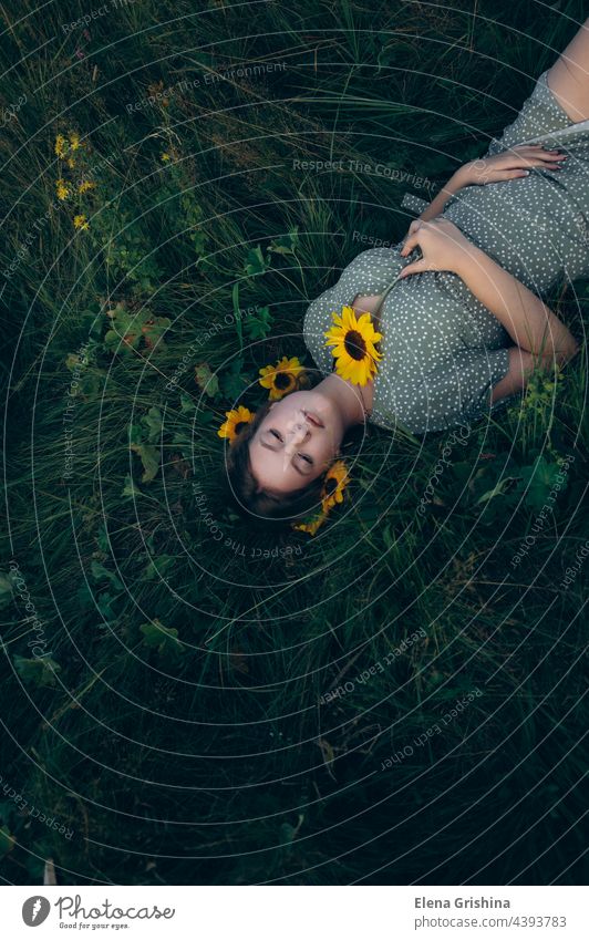 Portrait of a young girl lying on the grass among flowers. portrait sunflower dress summer beautiful femininity smile hair chain pendant youth rest slowdown