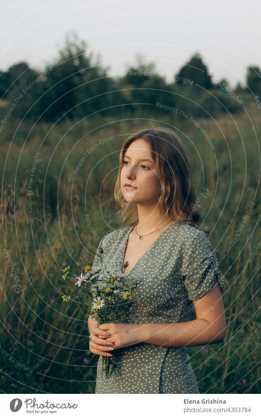 A young girl holds a bouquet of wildflowers in her hands. cottagecore aesthetics fresh air countryside slow life pastoral life caring sustainable vintage nature