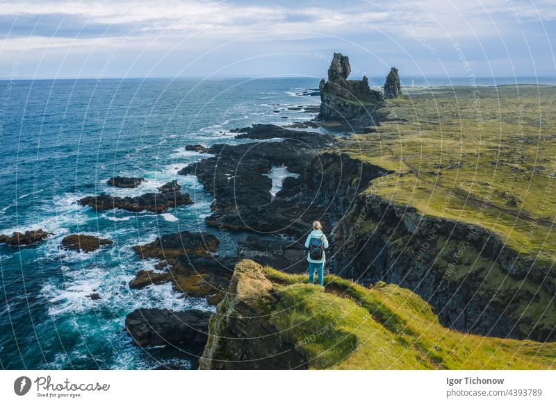 Man hiker in yellow jacket stand on the peak of the rock in outdoor park in Iceland. Londrangar londrangar iceland coast peninsula snaefellsnes lava formations