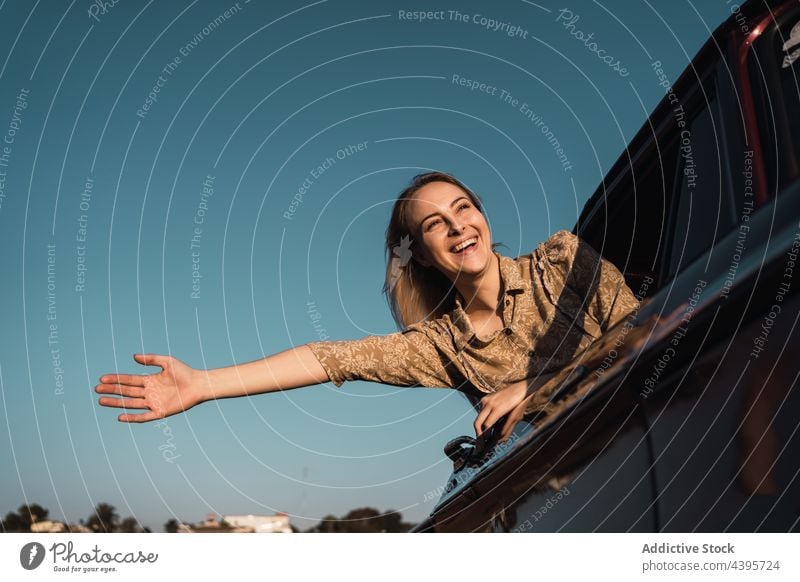 Carefree woman sticking out of car window stick out carefree freedom enjoy summer cheerful happy female nature evening vehicle sunset sunlight blue sky