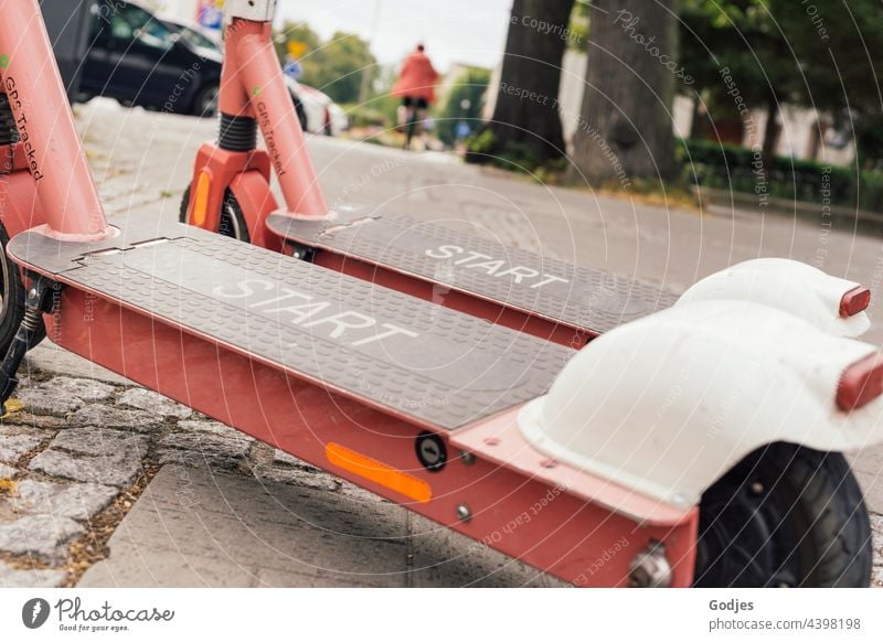 Two electric scooters on the side of the road with the inscription Start, a cyclist blurred in the background e-roller Transport Street Exterior shot Electric