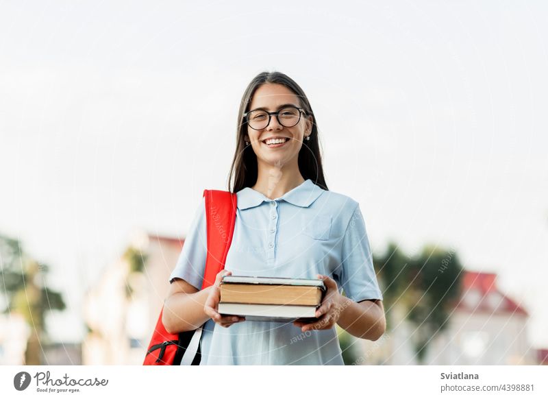 A cheerful student girl with a backpack and books, standing and smiling on the street smile university park attractive education campus school woman young