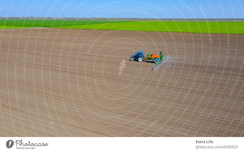 Aerial view on tractor as spraying field with sprayer, herbicide and pesticide Above Aerosol Agricultural Agriculture Arable Biochemical Biohazard Care Cereal