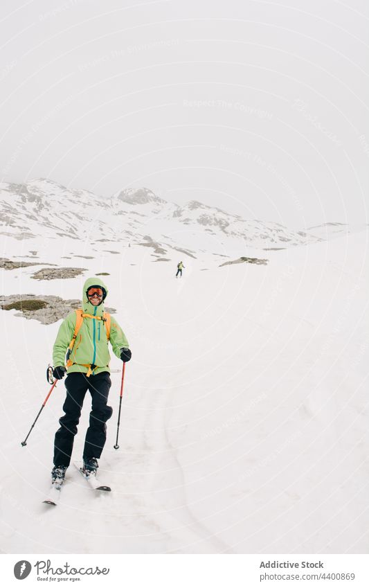 Smiling skier in goggles on snowy ridge in winter skiing sport mountain smile nature highland man sportspeople friend partner together activity recreation