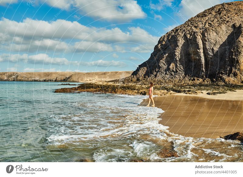 Woman standing near waving sea on beach woman wave tourist summer vacation cliff blue sky cloudy fuerteventura spain canary islands female coast shore resort