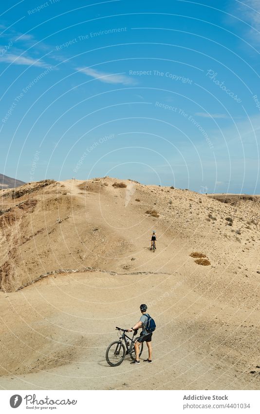 Cyclist riding bikes on sandy hill cyclist ride countryside bicycle watch route summer hobby travel fuerteventura spain canary islands adventure nature activity