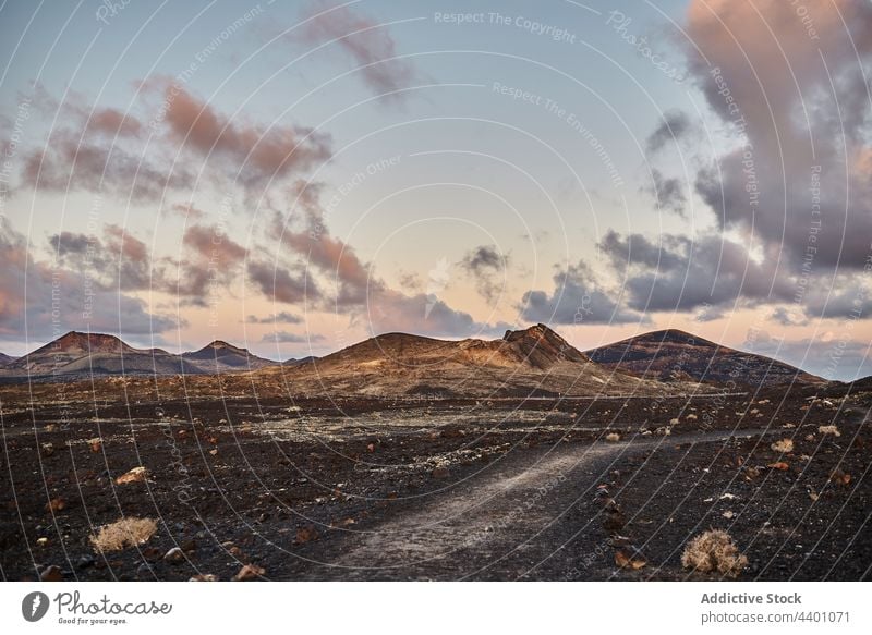 Path in arid valley near mountains path sunset nature cloudy sky highland route fuerteventura spain canary islands evening range landscape road rock ridge