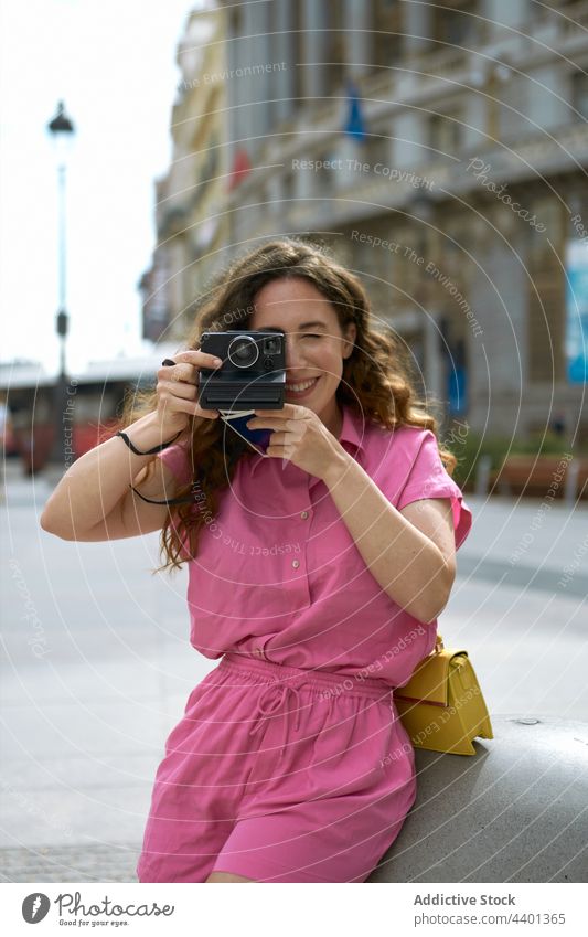 Smiling woman taking photo on instant camera in town take photo photo camera focus memory moment cheerful using device photography wink smile style sincere