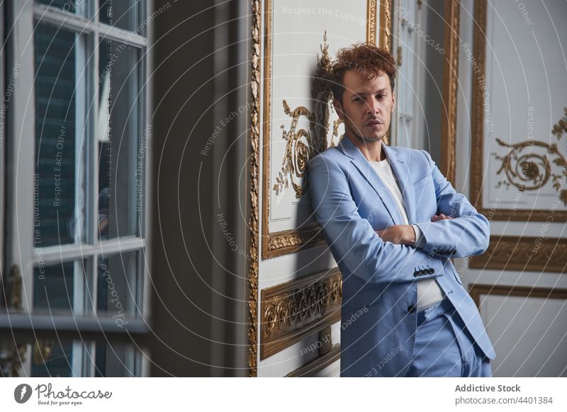 Pensive man in suit in luxury room arms crossed thoughtful sad pensive male style lean wall guy rich posh stand appearance concern well dressed mood indoors