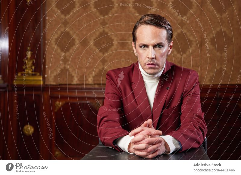 Actor sitting in table in suit in retro style studio man actor perform classy elegant communicate male art adult self assured confident respectable gentleman