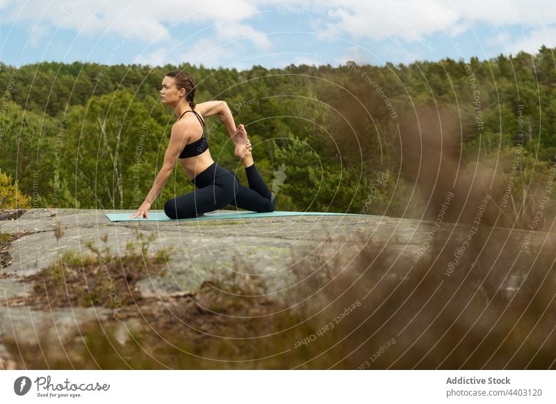 Flexible woman doing Mermaid pose on rock stretch yoga stone nature energy balance mermaid pose flexible barefoot female asana body fit practice wellness young