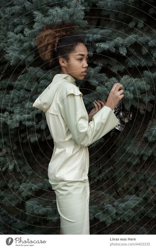 The hot days are almost gone, and our gorgeous model is hiding in these pines from upcoming autumn. Dressed in a white latex raincoat, with her pretty dark curly hair, and accidental posing. During the Ukrainian Fashion Week in Kyiv.