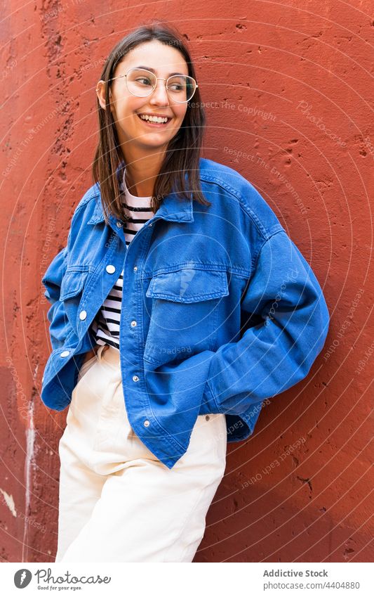 Happy woman smiling on sunny day in city cheerful delight style urban street female building wall smile trendy outfit colorful leaning positive happy joy glad