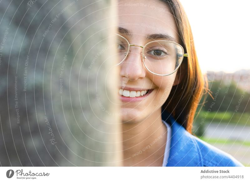 Woman peeping out of tree in park woman peep out peek out cheerful smile content glasses positive female happy charming joy city urban style enjoy glad carefree