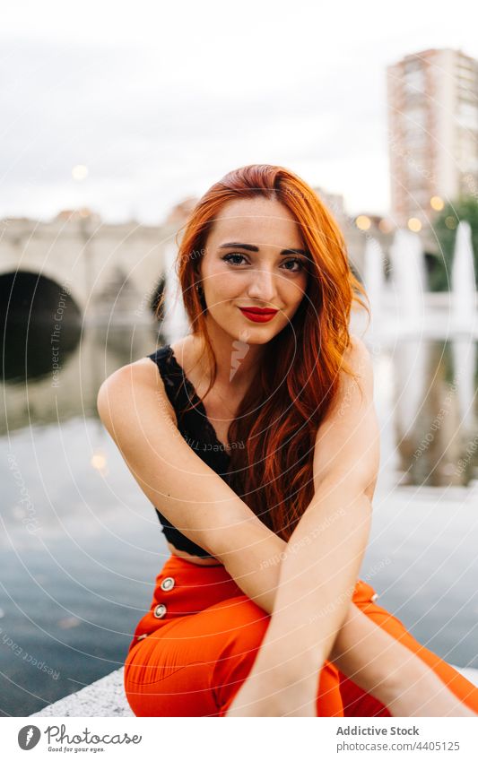 Trendy redhead woman on embankment in city style trendy pants orange bright color female vivid vibrant positive happy smile urban enjoy carefree content modern