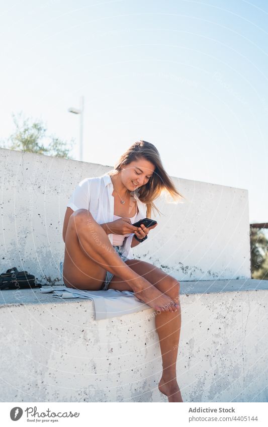 Smiling woman browsing smartphone in street city summer moment female happy cheerful text message mobile device smile cellphone using gadget urban enjoy