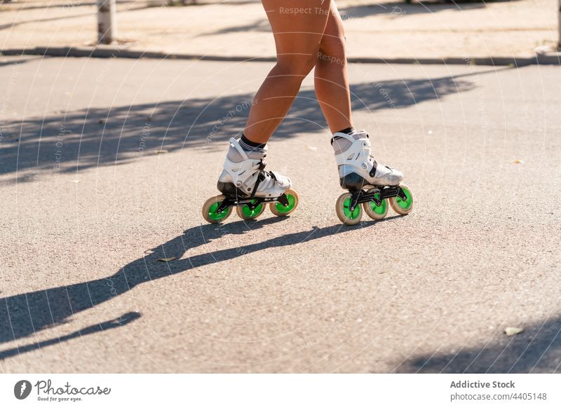 anonymous woman in rollerblades and showing stunt trick equilibrium skater summer wheel street female activity practice sunny sunlight summertime legs body part