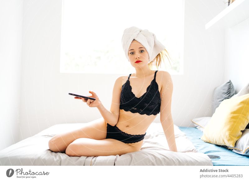 Content woman browsing smartphone on bed in morning using surfing drink cup enjoy female mobile cheerful device gadget happy internet smile coffee comfort