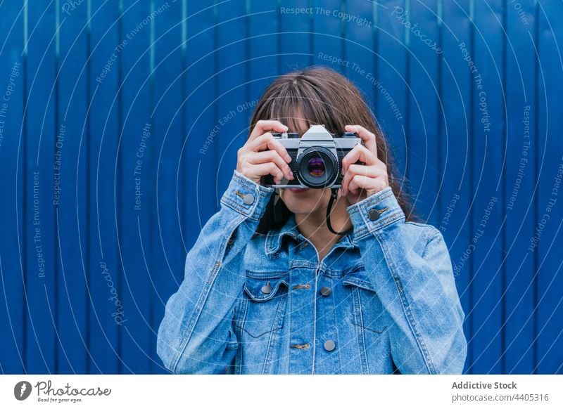 Unrecognizable woman taking photo on retro camera against blue wall photographer photo camera take photo vintage color memory moment female hobby photography