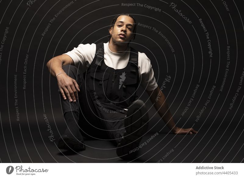 Young man with braids in dark studio style fashion afro confident model contrast hipster male ethnic black african american appearance young serious