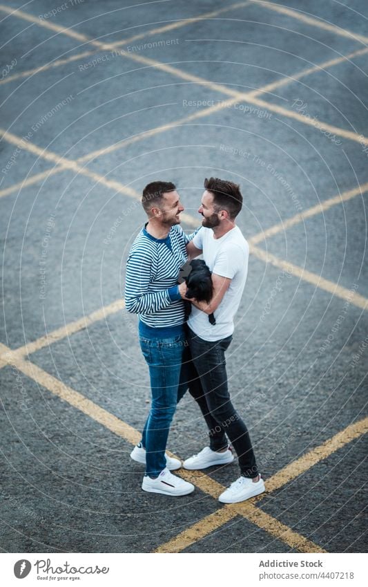 Happy couple of gays embracing dog in the street embrace happy canine pet animal companion port men same sex relationship spend time sincere homosexual smile