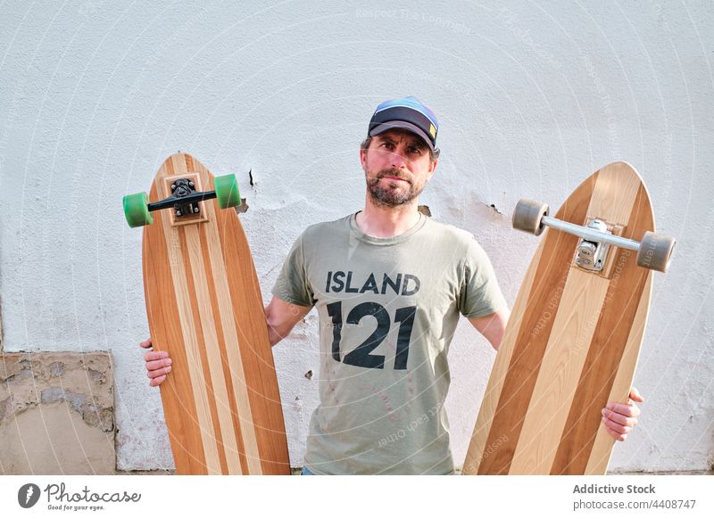 Skater with longboards on pavement in sunlight skater handmade creative design style sport modern man jeans wall skateboard contemplate street skateboarder dry