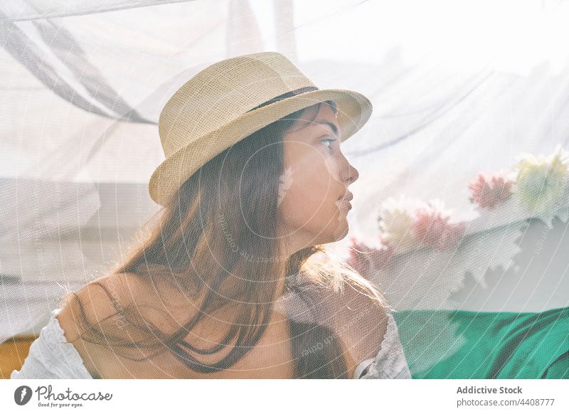 Young woman in sunhat sitting in tent summer content curtain young chill enjoy backyard female smile tranquil peaceful transparent serene harmony sunlight