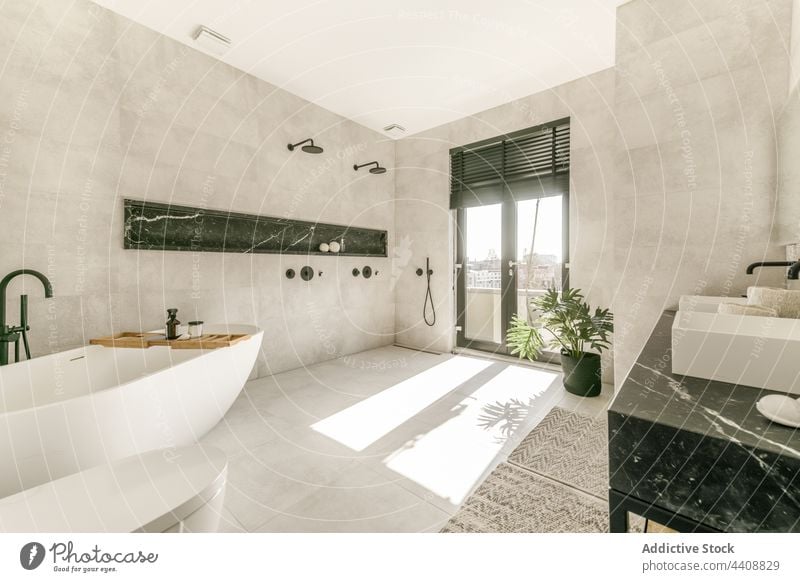 Interior of contemporary spacious bathroom interior minimal style modern ceramic bathtub design hygiene toilet sink tile sanitary restroom sunlight sunny simple