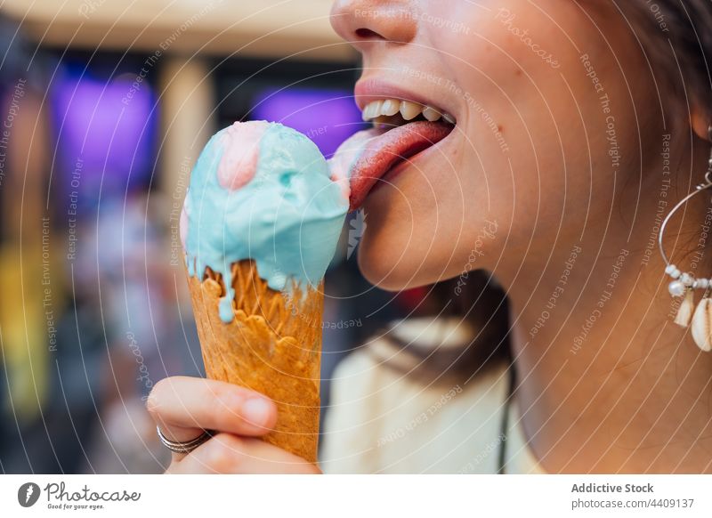 Crop woman enjoying delicious ice cream cone on street lick waffle dessert treat sweet crunchy gelato flavor pleasure tasty smile tongue out yummy smooth creamy