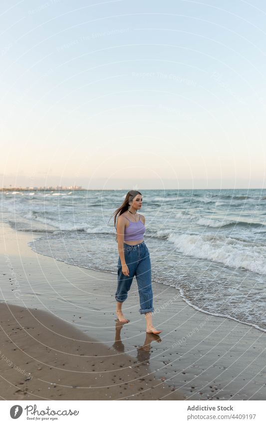 Barefoot female walking near sea waves woman evening beach wet weekend sand water barefoot coast shore nature summer vacation young ocean seaside sunset