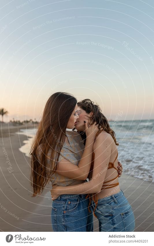 Lesbian couple kissing on beach women lesbian sea sundown hug love date female girlfriend romantic together sunset coast embrace relationship vacation summer