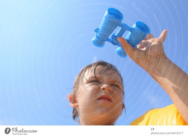 child looking through a toy binoculars outdoors looking away observe positive shore freedom vacation seaside enjoying carefree childhood casual cute day