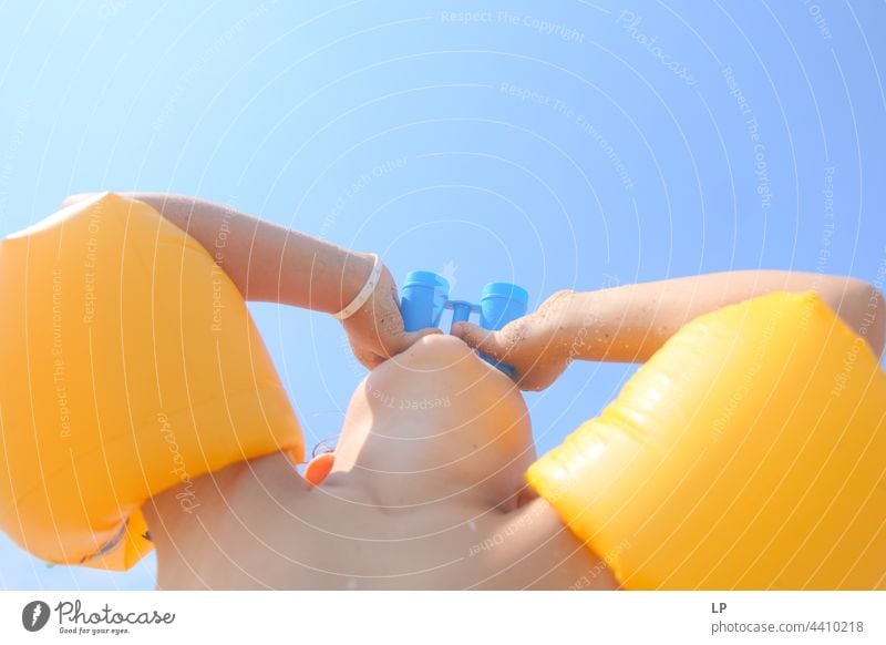 child looking through a toy binoculars outdoors looking away observe positive shore freedom vacation seaside enjoying carefree childhood casual cute day