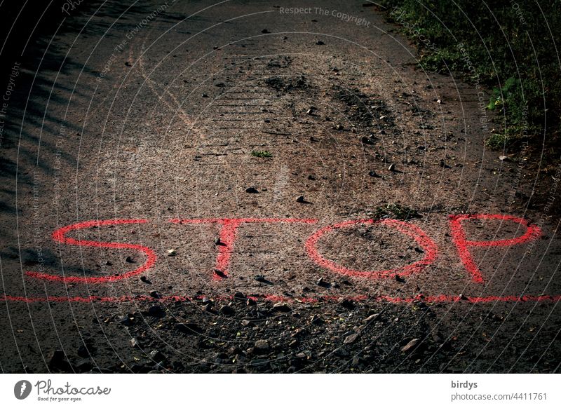 Stop. Red line, writing on an asphalted road, gravel stones lie on the road surface. stop red line Street Barred Safety Characters Command Bans symbol picture