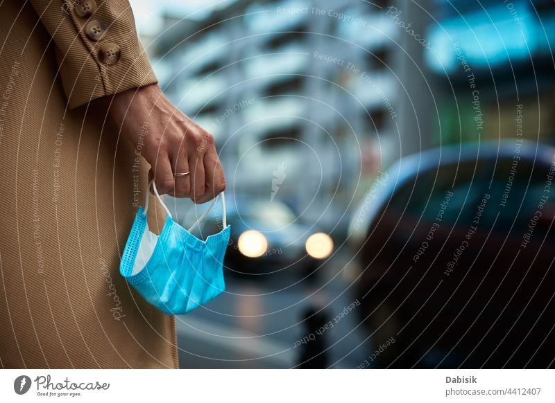 Woman holds protective mask in hands at city street woman walk coronavirus lockdown quarantine business coat stylish fashion bag go urban autumn face person