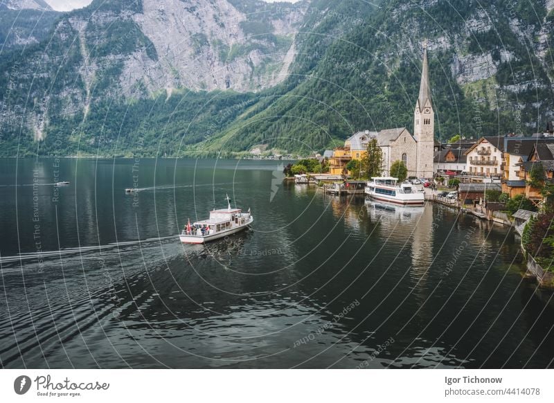 Mountain lake and tourist boat reaching Hallstatt village with Alps in background. Austria hallstatt austria view alps famous town landscape nature tourism