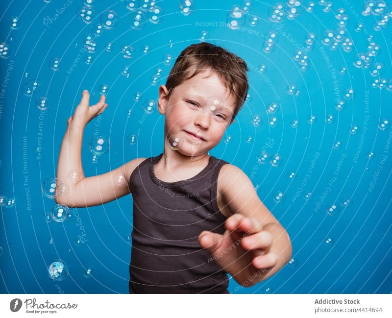 Child looking at camera in studio with soap bubbles child boy kid surprise childhood face expression wow reaction sign symbol indicate virtual display click