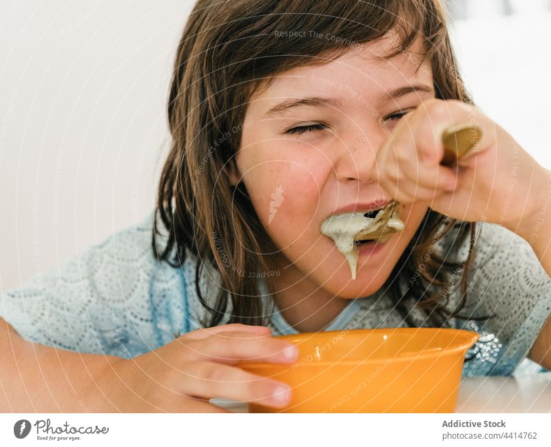 Funny girl eating cream soup during lunch child kid home delicious puree bowl table food meal childhood healthy nutrition cute yummy dish tasty spoon kitchen