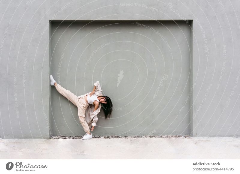 Graceful dancer performing near wall in city street woman cool style talent urban backbend flexible female leg raised move choreography lean grace skill energy