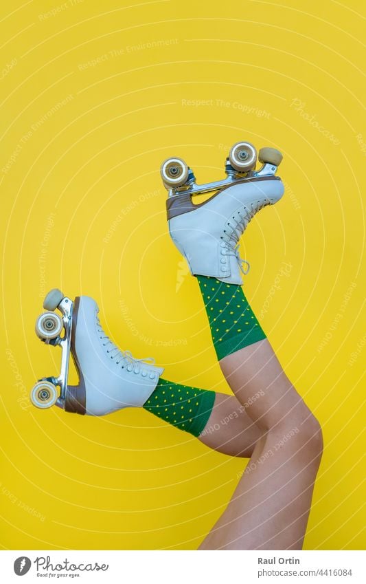 Woman with vintage quad roller skates and green socks on yellow background woman fun blade legs sport summer female lifestyle fashion boot skater foot fitness