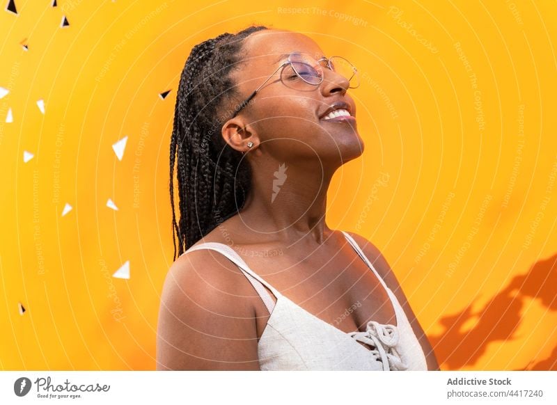 Delighted black woman with braids near yellow wall dreamy summer enjoy smile city vivid color carefree female ethnic african american barceloneta barcelona