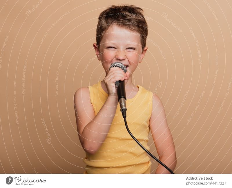 Preteen boy singing in microphone in studio child entertain cool singer style trendy music contemporary song audio sound perform kid modern playful childhood