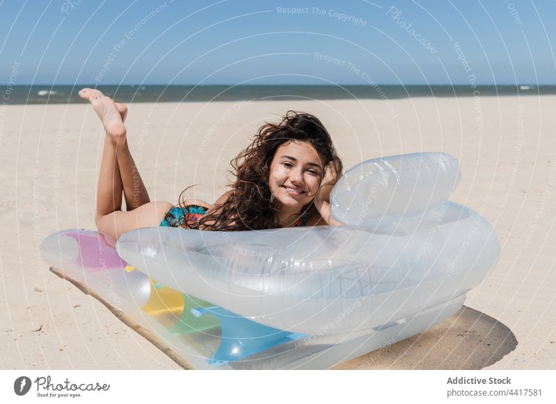 Cheerful woman sunbathing on inflatable mattress on beach suntan summer vacation swimsuit holiday female relax lying carefree pleasure sunlight summertime enjoy