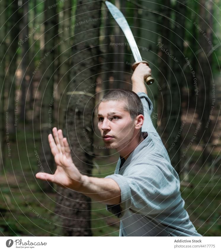 Kung fu warrior practicing with sword man kung fu forest training stance technique tradition practice male martial balance strong weapon lunge oriental