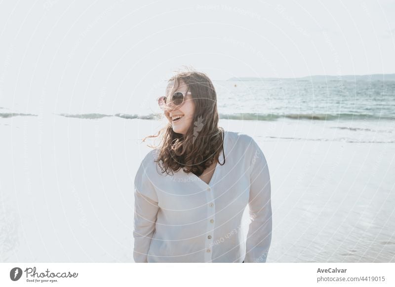 Happy young woman laughing and smiling at the beach on a summer day, enjoying vacation, concept of friendship enjoying the outdoor happiness arm carefree