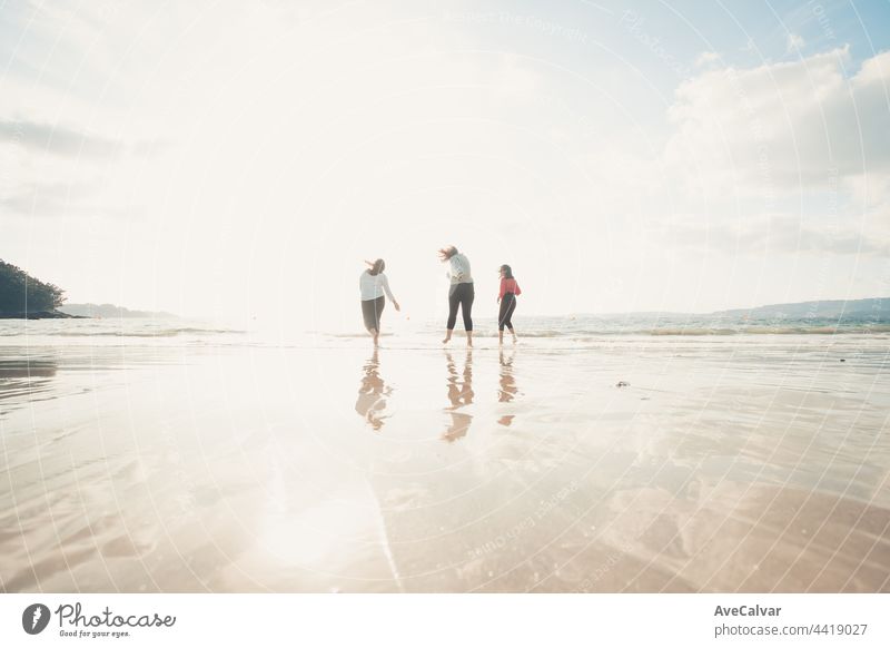 Happy women friends runs at sea beach during a bright day, friends happy relax having fun playing on beach near sea when sunset in evening. friendship party