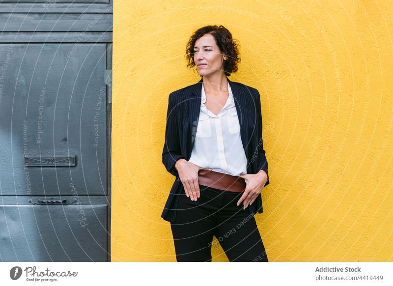 Confident well dressed woman standing near bright wall confident elegant formal personality appearance style respectable posture gaze female charismatic