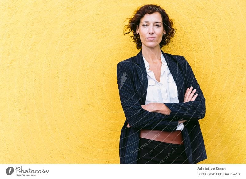 Confident well dressed woman standing near bright wall confident elegant formal personality appearance style respectable posture gaze female charismatic